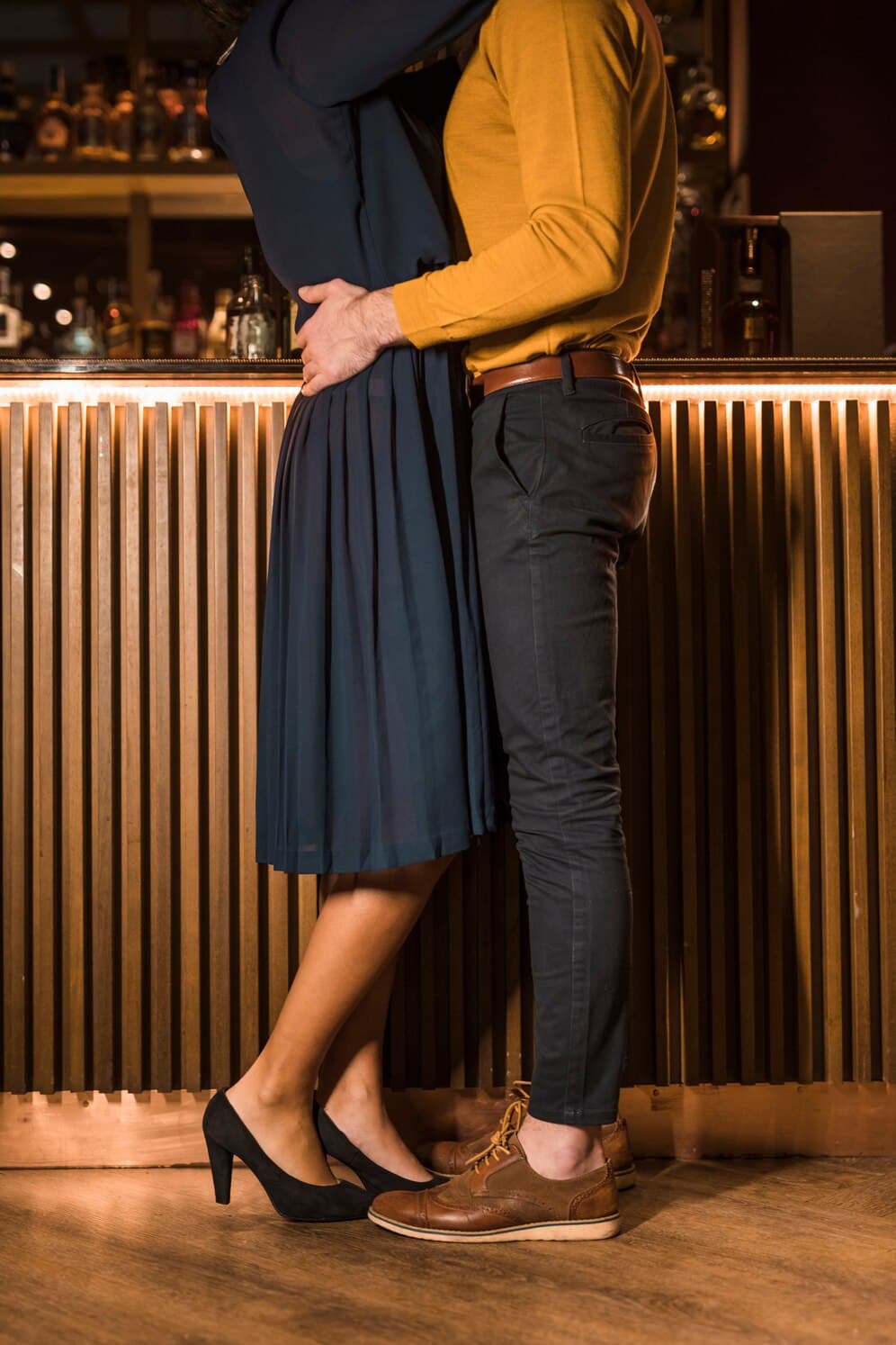 Young man hugging with slim woman near bar counter
